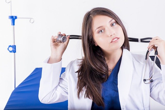 Ärztin mit Stetoskop vor Bett