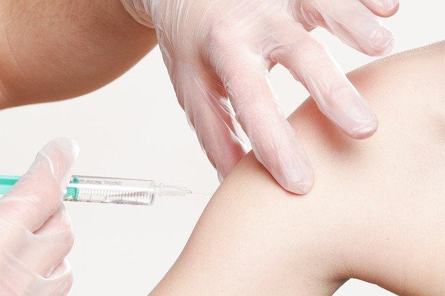 Impfung mit Spritze an der Schulter