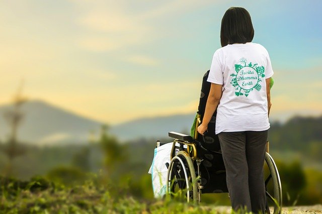 Junge Frau mit Rollstuhl vor sich schaut zum Horizont